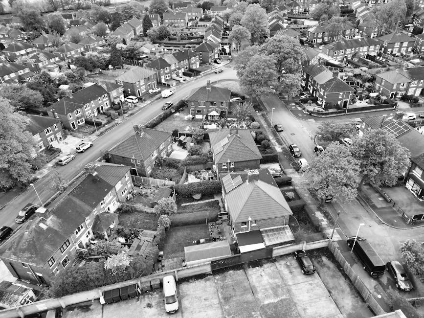 A row of Victorian-style terraced houses with ornate white metal balconies and bay windows situated behind a brick wall with small landscaped gardens, located on a residential street during daylight hours under a partly cloudy sky. In the foreground, there are multiple black wheelie bins lined along the pavement, indicating local waste collection, with a dark grey van parked nearby, possibly used for home relocation or furniture transport by Man with Van Addiscombe. The scene captures the typical urban setting for house removals and moving services, illustrating a professional environment for loading and unloading possessions during a house move or residential clearance, with the houses' architecture suggesting an older, established neighbourhood in the Croydon area. The presence of clear weather, well-maintained gardens, and accessible street features highlights the typical logistical environment for professional removals in London suburbs.